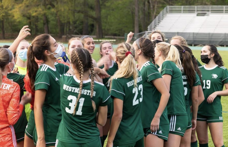 The Varsity Girls soccer team huddles up before a game to get in the winning spirit. 