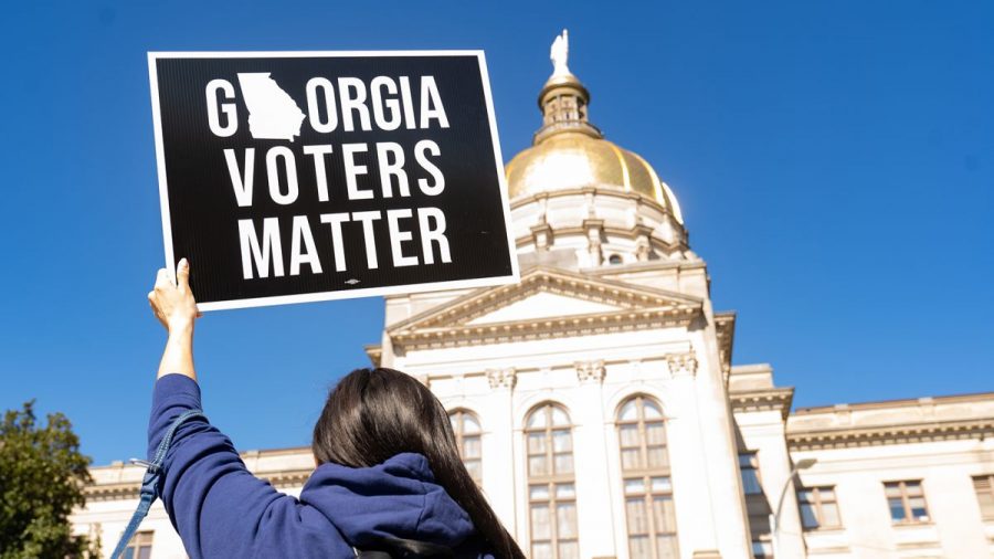 A protestor of the state bills which limit voting rights holds up a sign at the State Capitol.